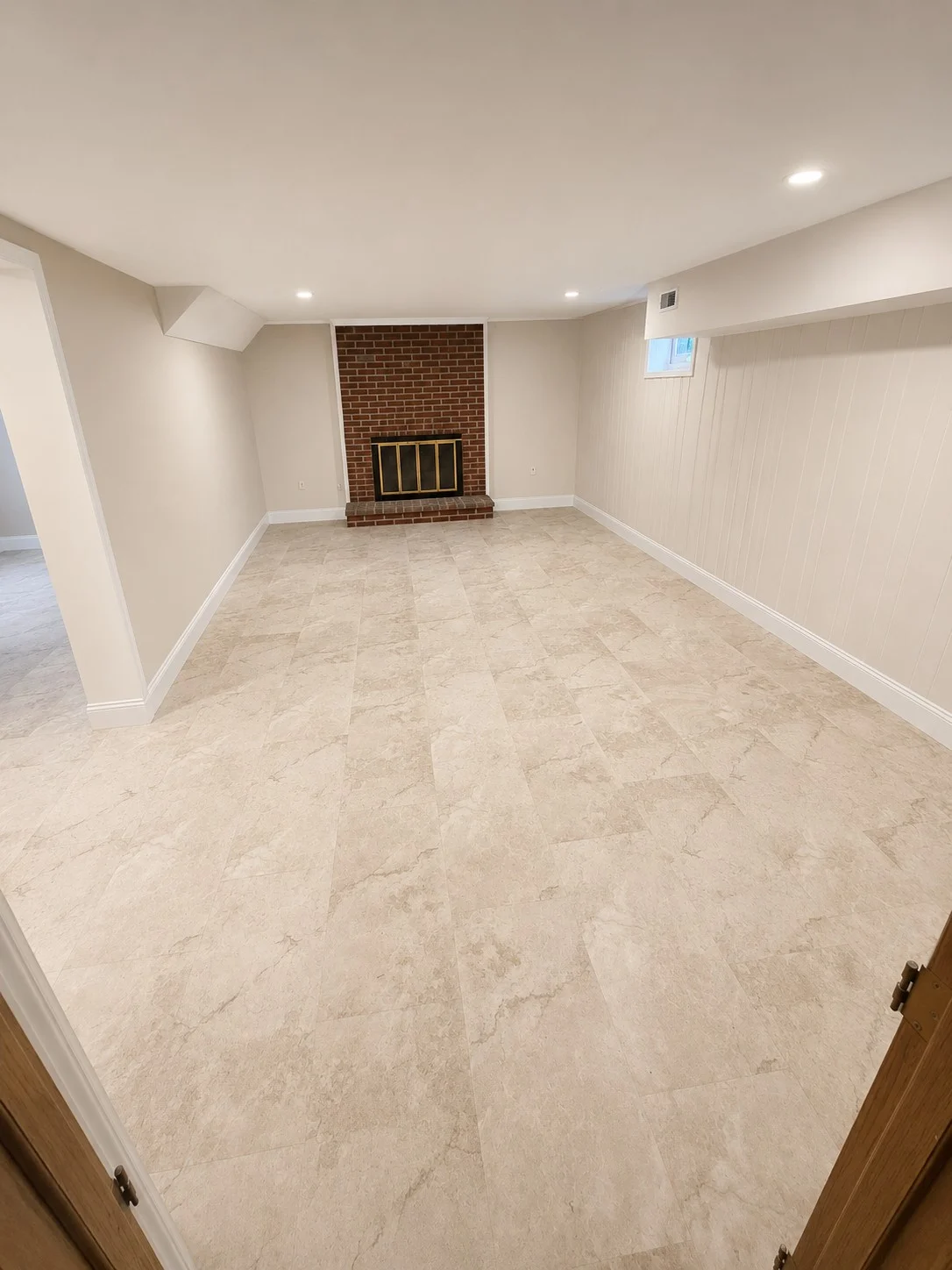 Remodeled basement family room with luxury vinyl flooring and brick fireplace in Johnson City, TN