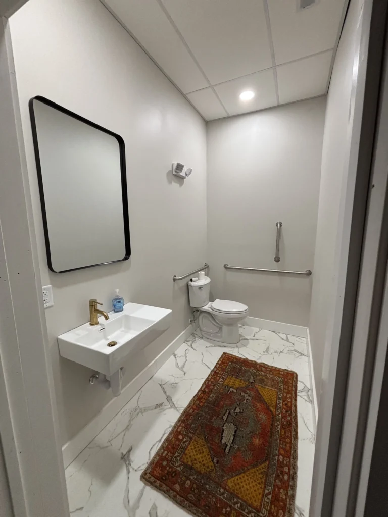 Finished commercial office bathroom with wall-mounted sink and ADA grab bars in Bristol, TN
