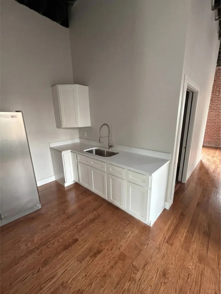 Bristol VA downtown loft kitchen remodel featuring custom white shaker cabinets, quartz countertops, undermount sink, and hardwood flooring