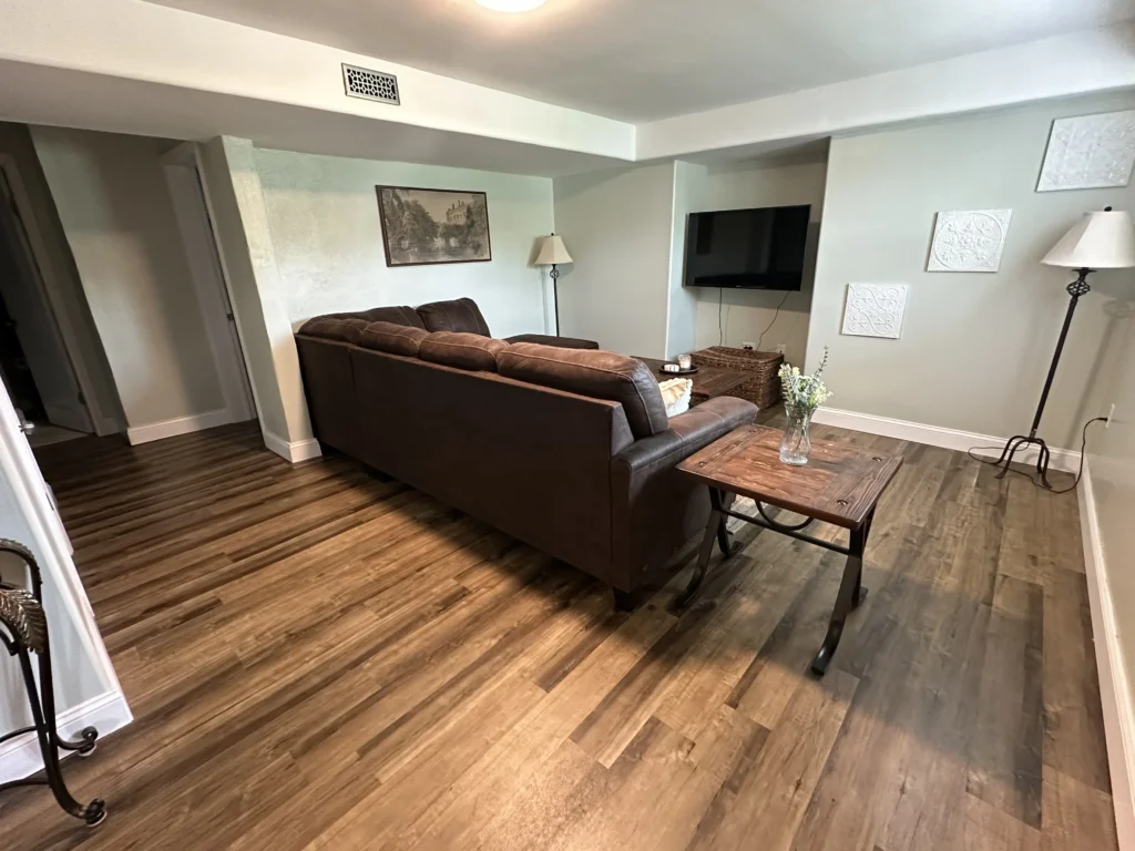 Living room with new LVP flooring and wood accent wall in Johnson City basement remodel